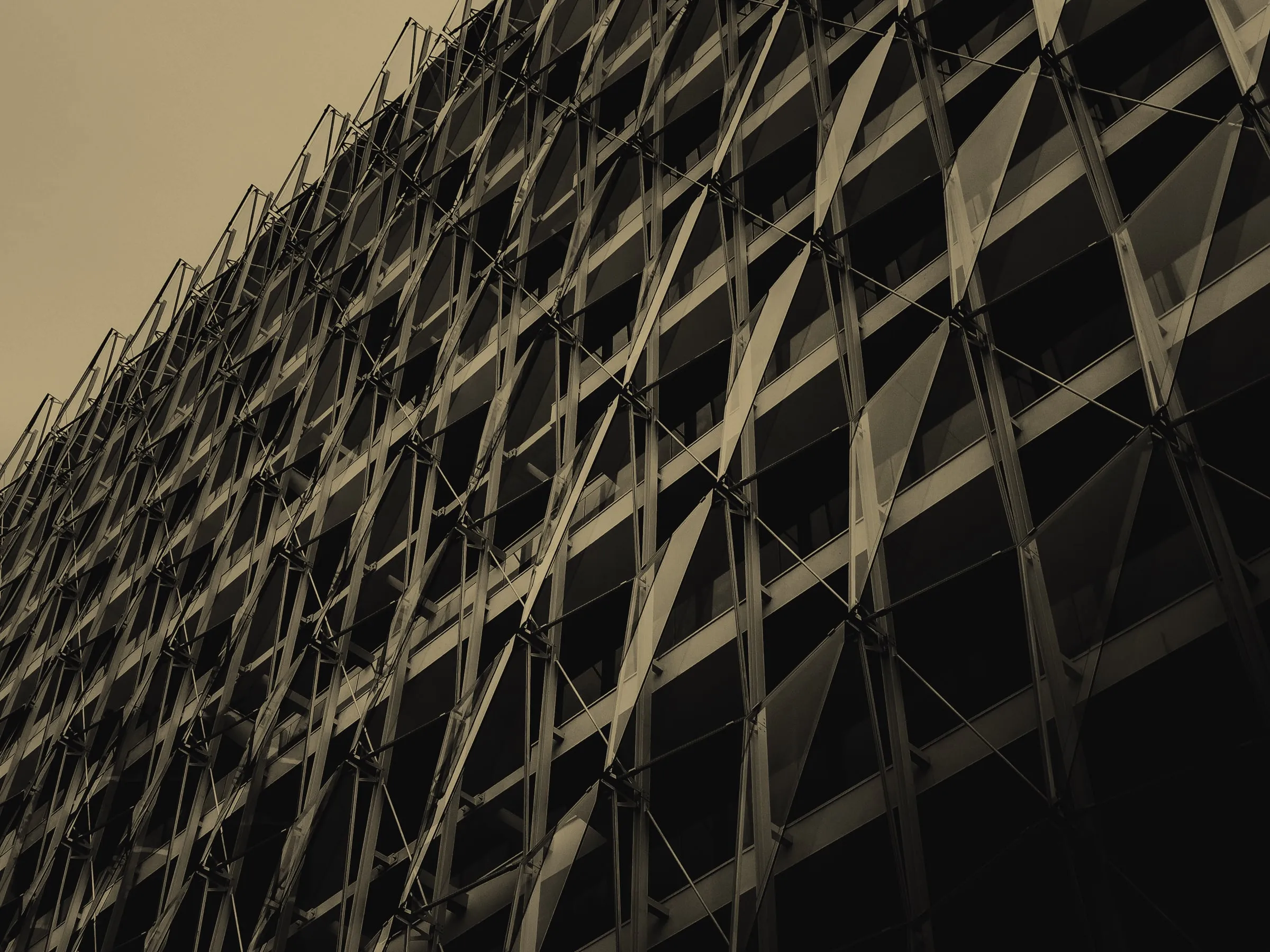 The steel lattice façade of a modern building, viewed from below.